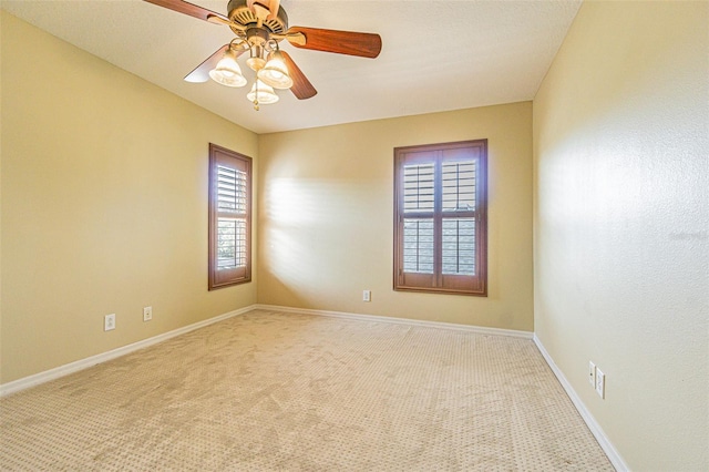 spare room featuring light carpet, ceiling fan, and baseboards