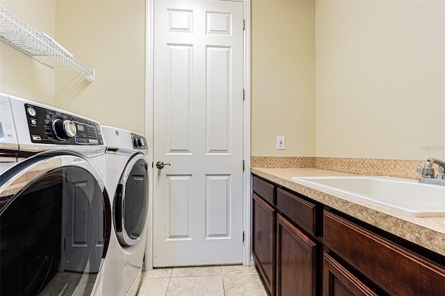 laundry area featuring light tile patterned floors, cabinet space, separate washer and dryer, and a sink