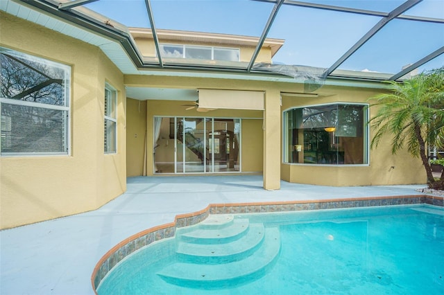 pool featuring glass enclosure, a ceiling fan, and a patio