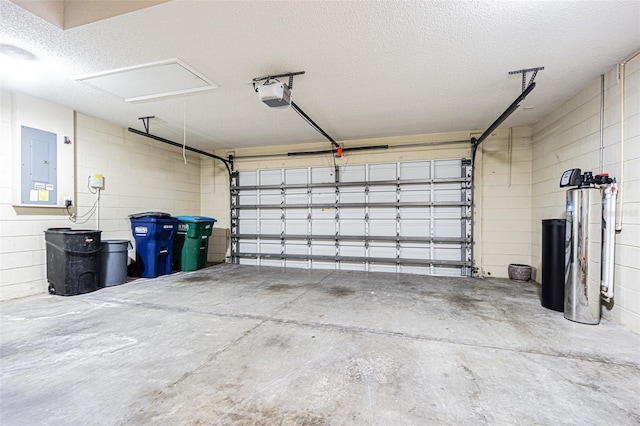 garage featuring concrete block wall, electric panel, and a garage door opener