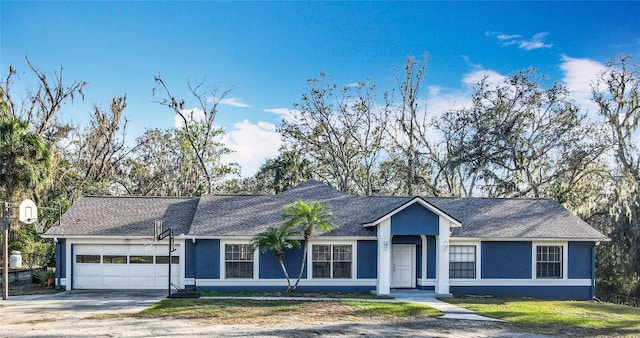 single story home with a garage, driveway, a front yard, and stucco siding