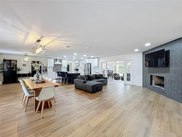 living room with a large fireplace, light wood-type flooring, and recessed lighting