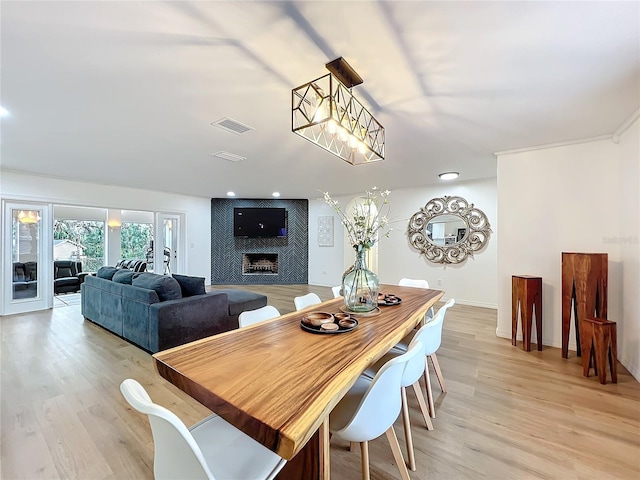 dining area with light wood-style floors, visible vents, a fireplace, and baseboards