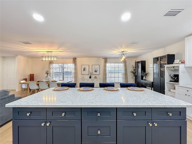 kitchen featuring light wood-style flooring, a notable chandelier, visible vents, open floor plan, and a center island