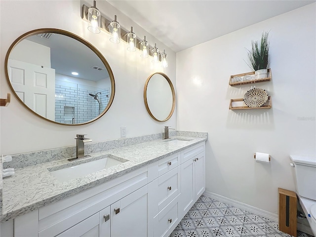 bathroom with double vanity, a sink, toilet, and baseboards