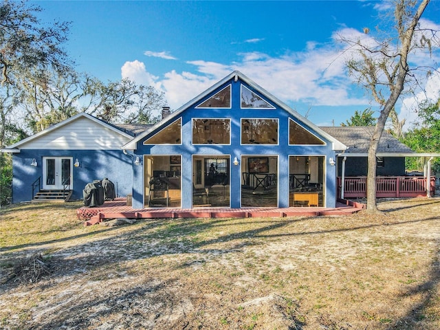 back of property with french doors, a sunroom, a chimney, a deck, and a yard