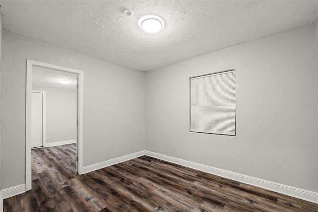 unfurnished room featuring dark wood finished floors, a textured ceiling, and baseboards