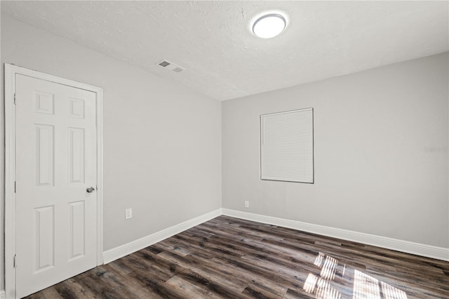 empty room featuring baseboards, a textured ceiling, visible vents, and dark wood-style flooring