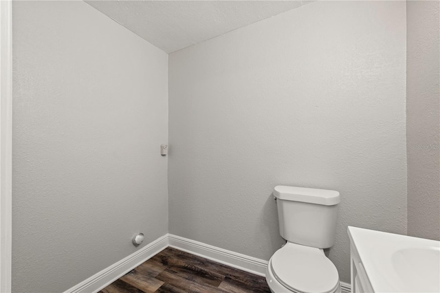 bathroom with vanity, wood finished floors, toilet, and baseboards