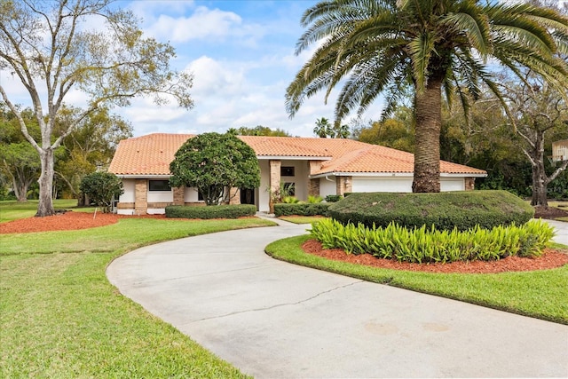 mediterranean / spanish house with a tiled roof, stucco siding, concrete driveway, and a front yard