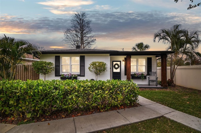 single story home with covered porch and fence