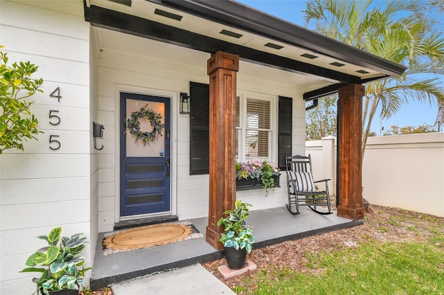 entrance to property featuring a porch and fence