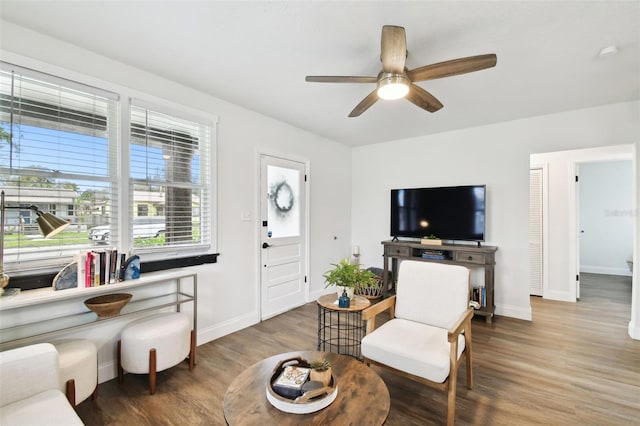 living room featuring wood finished floors, a ceiling fan, and baseboards