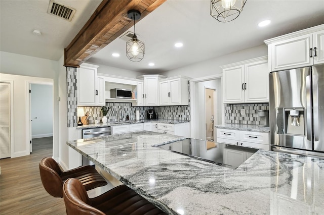 kitchen with stainless steel appliances, a sink, visible vents, white cabinetry, and beamed ceiling