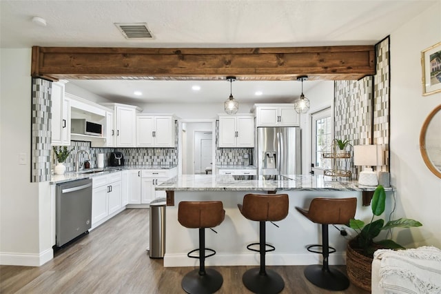 kitchen featuring a kitchen bar, light stone counters, stainless steel appliances, and beamed ceiling