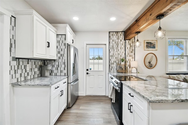 kitchen with electric range oven, a peninsula, stainless steel fridge, and white cabinetry