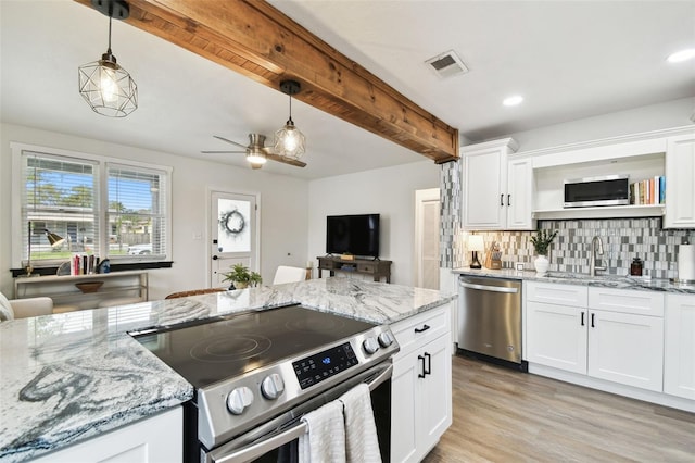 kitchen featuring beam ceiling, stainless steel appliances, tasteful backsplash, visible vents, and a sink