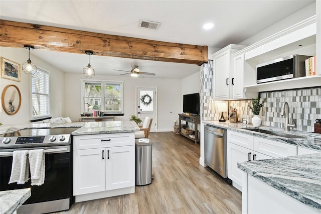 kitchen featuring a sink, visible vents, appliances with stainless steel finishes, tasteful backsplash, and beamed ceiling