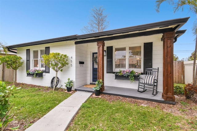 view of front of property featuring a porch, a front yard, and fence