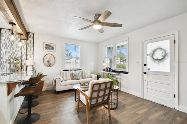 living room with dark wood finished floors, a ceiling fan, and baseboards