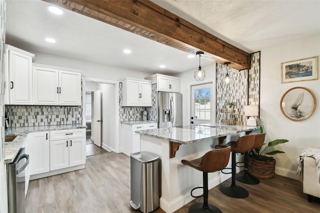 kitchen featuring stainless steel appliances, light wood-style flooring, and light stone countertops