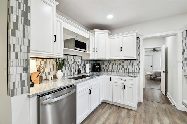 kitchen featuring white cabinets, a ceiling fan, light wood-style flooring, stainless steel dishwasher, and a sink