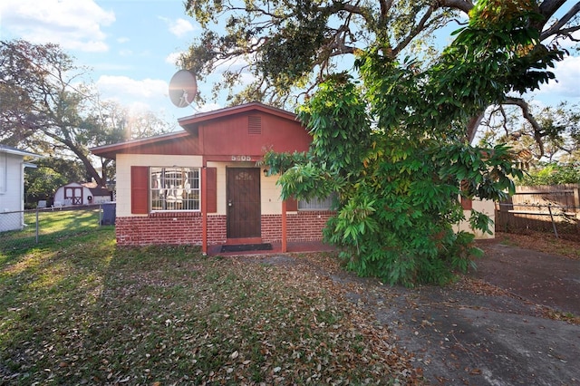 view of front of property with a front yard, fence, and brick siding