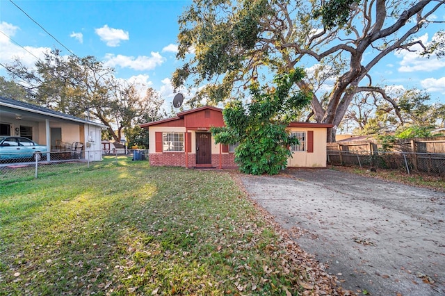 view of front of property featuring brick siding, concrete driveway, a chimney, fence, and a front yard