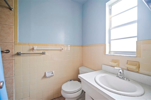 bathroom featuring toilet, a wainscoted wall, tile walls, and vanity