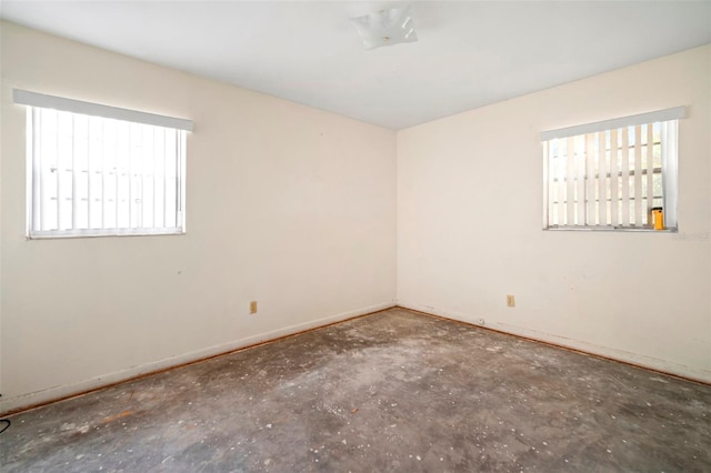 spare room with baseboards, concrete floors, and a healthy amount of sunlight