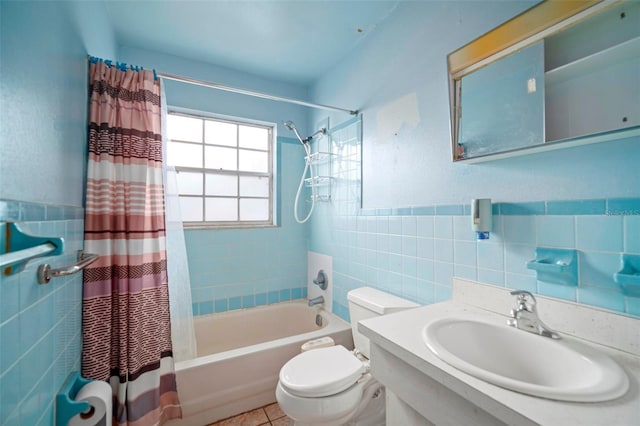 full bath featuring toilet, tile patterned flooring, shower / bathtub combination with curtain, vanity, and tile walls