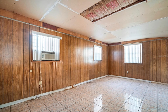 unfurnished room featuring wooden walls, baseboards, and cooling unit