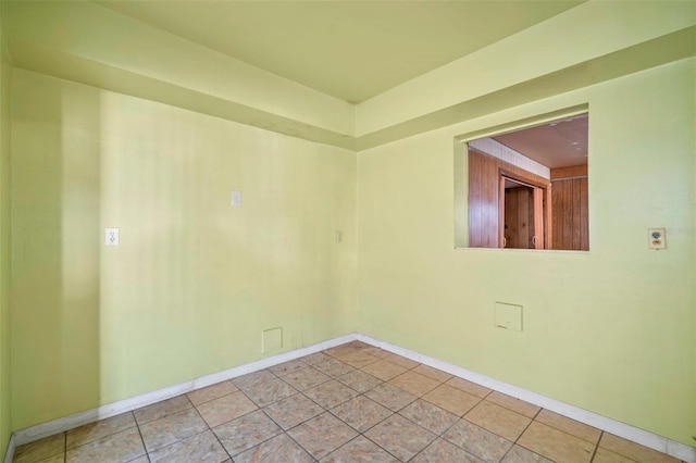 spare room featuring light tile patterned flooring and baseboards