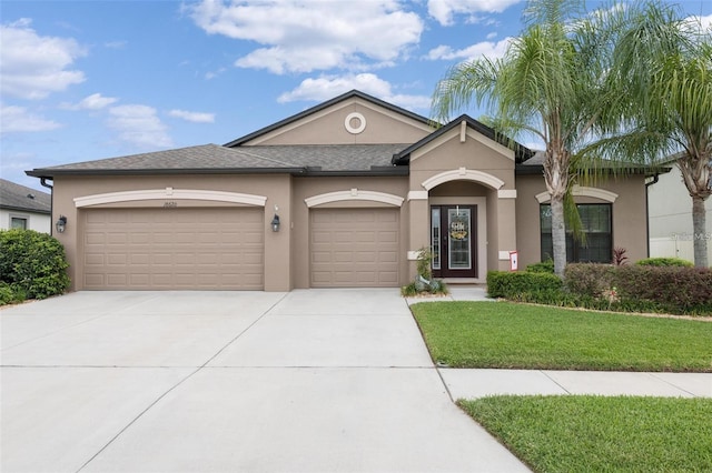 view of front of property with a garage, concrete driveway, a front yard, and stucco siding