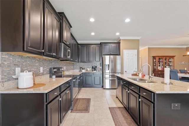 kitchen with light tile patterned floors, stainless steel appliances, a sink, decorative backsplash, and an island with sink