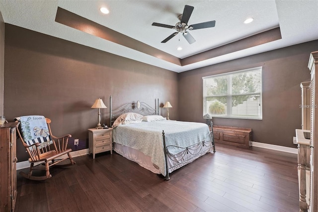 bedroom featuring dark wood-style floors, ceiling fan, baseboards, and a raised ceiling