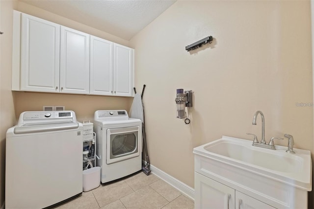 washroom with light tile patterned floors, a sink, baseboards, washer and dryer, and cabinet space