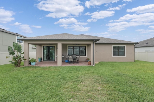 rear view of house with a ceiling fan, fence, a yard, a patio area, and stucco siding