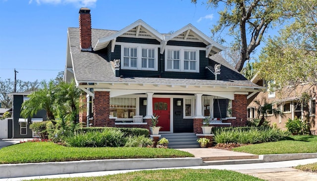 view of front of home featuring brick siding, a porch, and a chimney