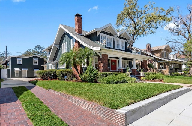 view of front of home featuring brick siding, a front yard, and a chimney