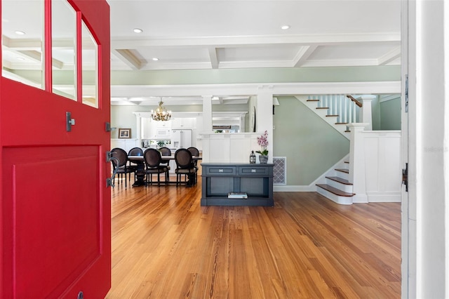 interior space featuring stairway, coffered ceiling, beamed ceiling, and wood finished floors