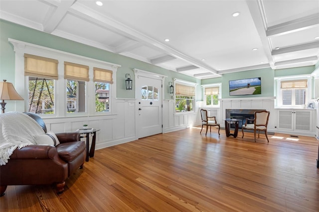 entrance foyer featuring beamed ceiling, wood finished floors, coffered ceiling, and a tile fireplace