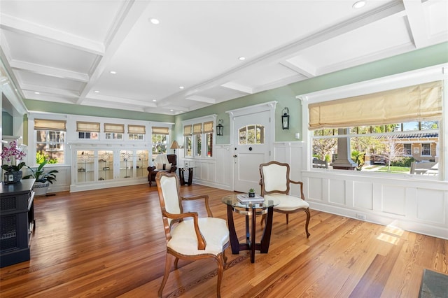 living area with a wealth of natural light, beam ceiling, coffered ceiling, and wood finished floors