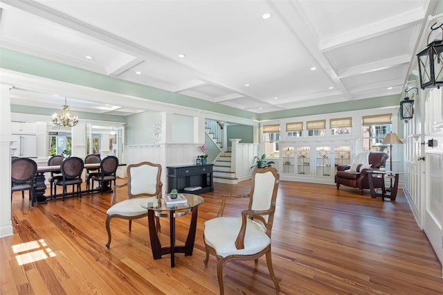 living room with beamed ceiling, stairs, wood finished floors, a notable chandelier, and coffered ceiling