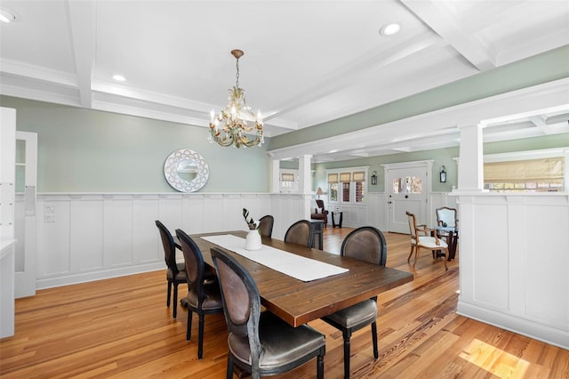 dining area with a wainscoted wall, decorative columns, beam ceiling, light wood-style floors, and coffered ceiling