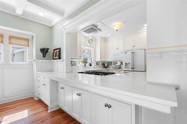 kitchen with light wood-style flooring, white appliances, a peninsula, white cabinets, and light countertops