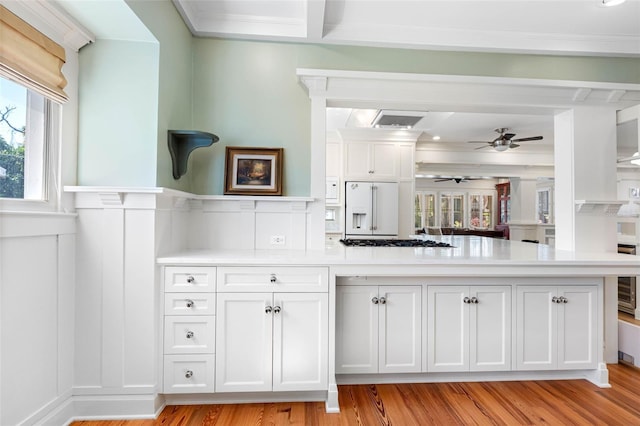 kitchen with light wood-type flooring, light countertops, white fridge with ice dispenser, white cabinets, and gas stovetop