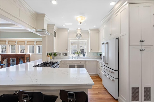 kitchen with light wood-style flooring, a sink, high end white fridge, recessed lighting, and a peninsula