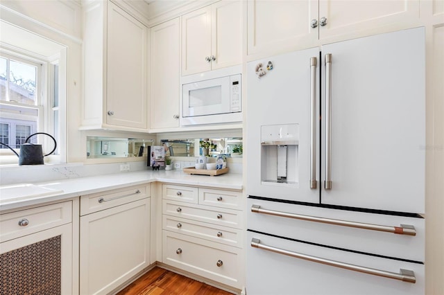 kitchen featuring white cabinetry, white appliances, light wood-type flooring, and a sink