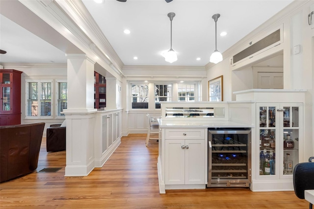 kitchen featuring light wood-style flooring, open floor plan, beverage cooler, and crown molding